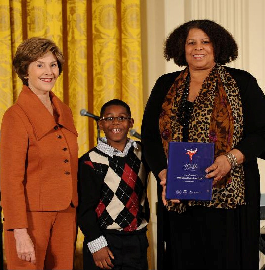 First Lady Laura Bush, YEA ensemble member Kamil McFadden, and Executive Director Debi Barber receiving the Coming Up Taller Award
